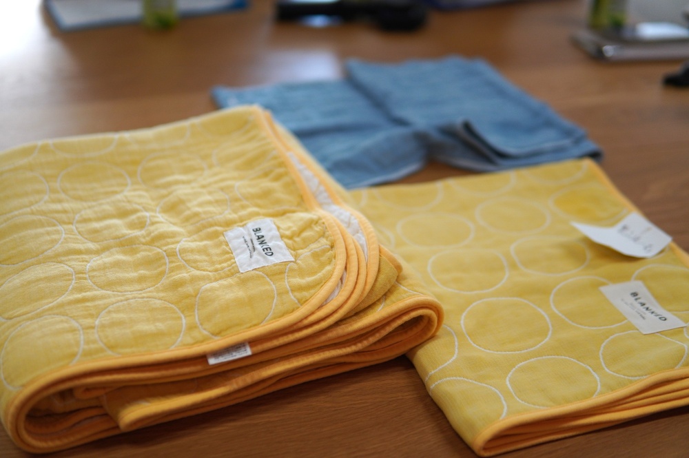 主力製品のひとつであるオリジナルブランド「BLANKED（ブランケット）」には、ナカモリさんのこだわりが凝縮されています。ブランド名があえて「BLANKED」と過去形になっているのには理由があります。それは「子供の時から使っていて、大人になっても『あれ良かったな』と思い出してもらえるような愛着の対象になってほしい」という願いと、「最初から使い込んでエイジングされたような風合い」を表現しているためです。この独特の風合いと高い吸水性を生み出す秘密は、こだわりの「洗い」の工程にあります。通常の仕上げで使われる水を弾きやすい柔軟剤を使わず、たっぷりの水と優しい酵素を使って時間をかけて洗い上げることで、購入した最初からふんわりと肌に馴染む柔らかさと、驚くほどの吸水性が引き出されています。